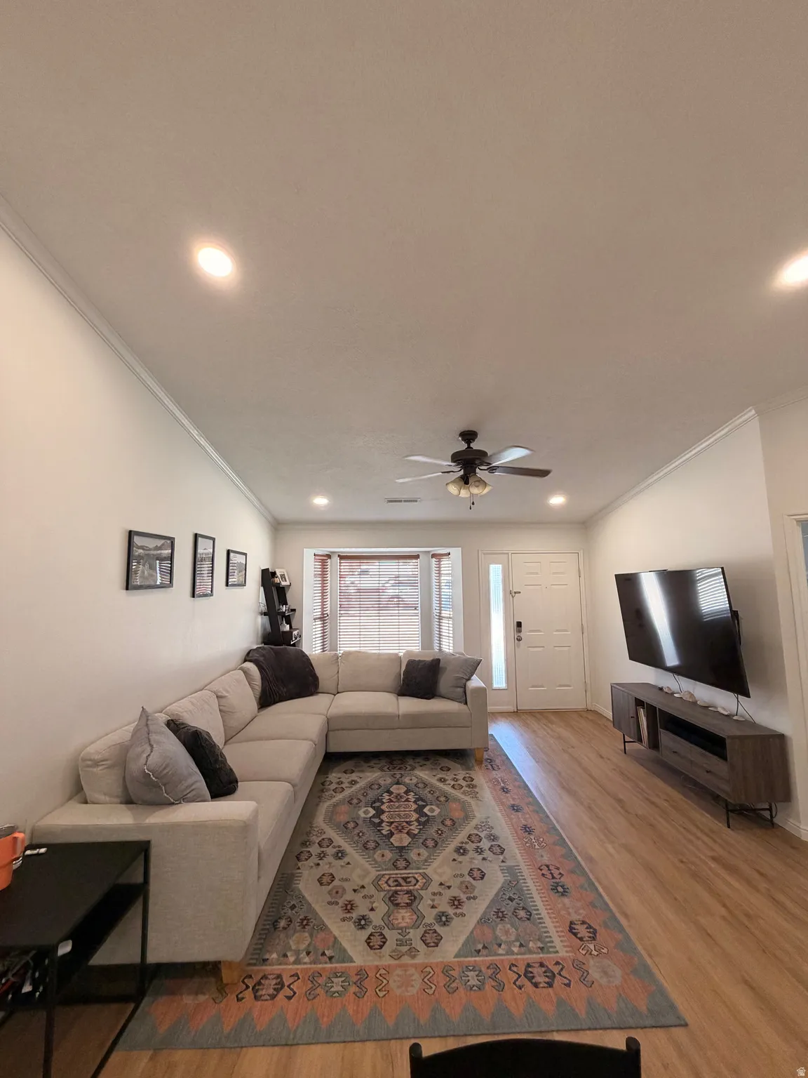 Living room featuring light wood-style floors, ornamental molding, ceiling fan, and recessed lighting