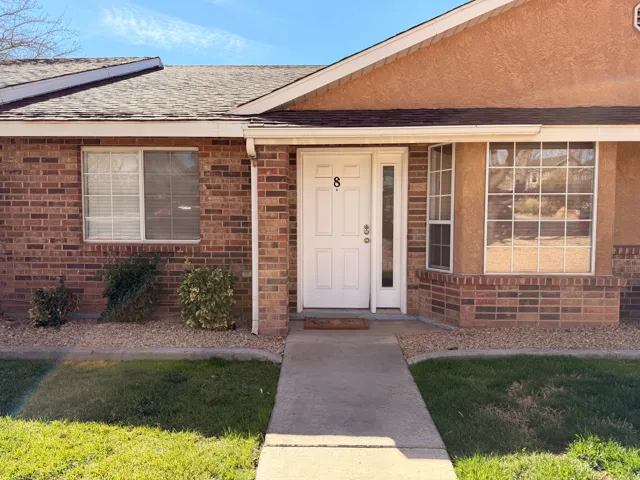 Doorway to property featuring roof with shingles, brick siding, and a porch