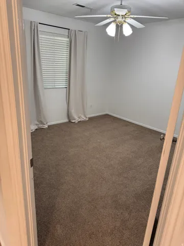 Neutral wall color, ceiling fan with integrated lighting, window with blinds, and brown carpet flooring