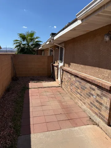 Private outdoor patio featuring red paver stones and a surrounding block wall