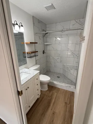 Walk-in shower with a built-in bench, marble-finish tile surround, and glass enclosure