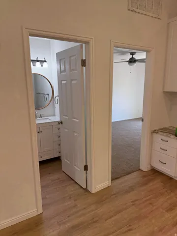 Wood-finish flooring throughout, white paneled doors, and ceiling fan with integrated lighting