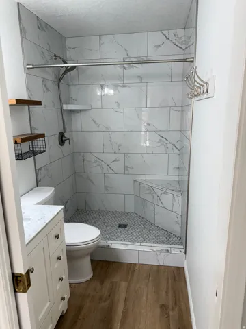 Walk-in shower with marble-look tile surround and mosaic tile floor