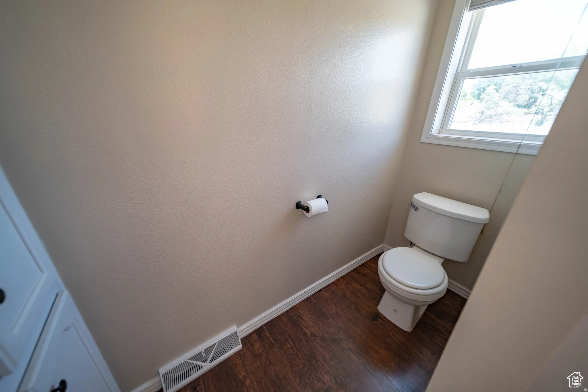 Master Bathroom with toilet and dark wood finished floors