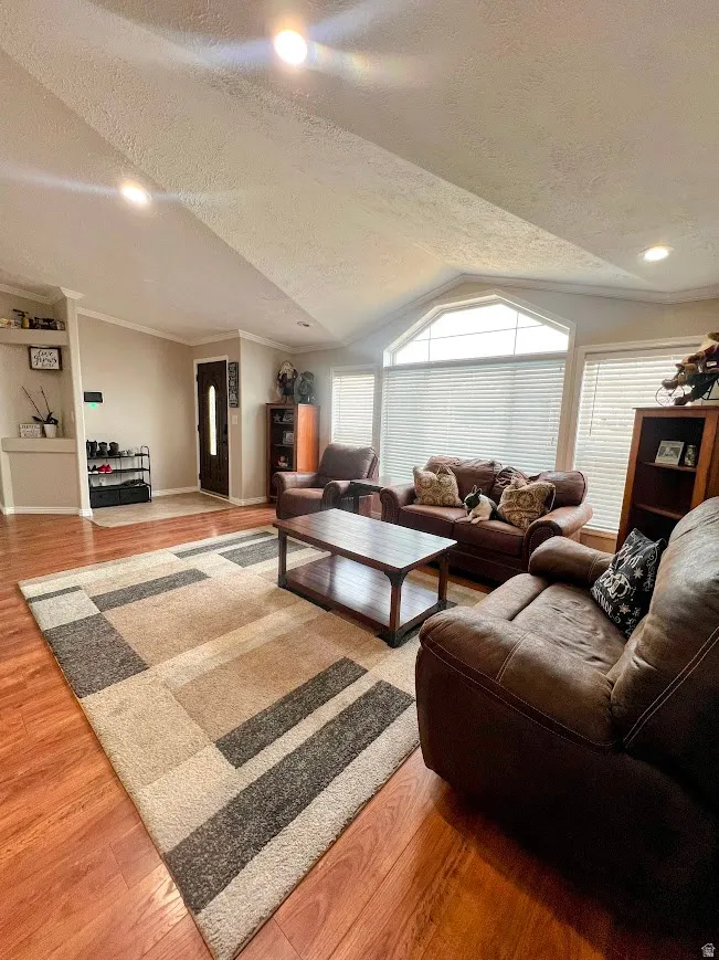 Living area with a textured ceiling, light wood-type flooring, and crown molding