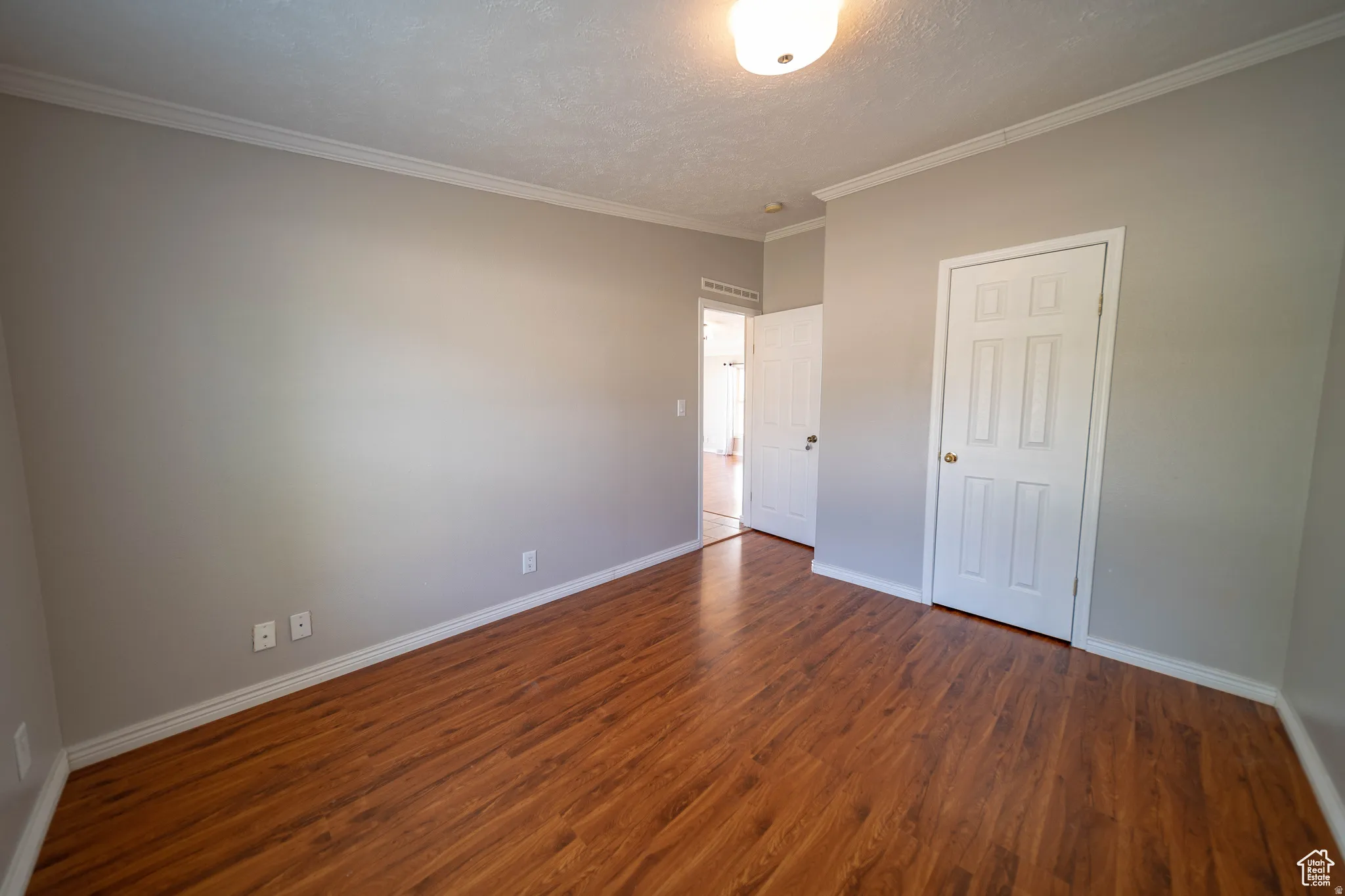 Bedroom 2 featuring a textured ceiling, dark wood-style floors, and ornamental molding