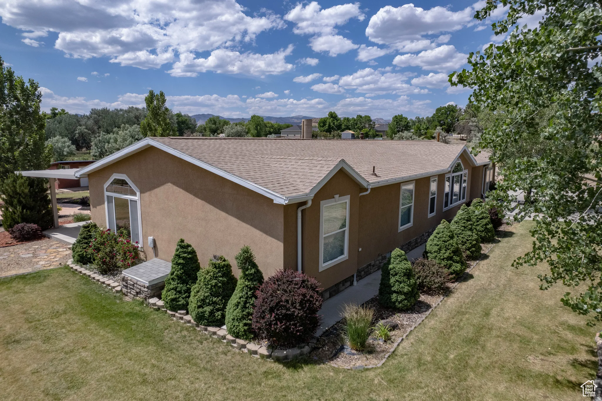 View of home's exterior with stucco siding, a lawn, and roof with shingles