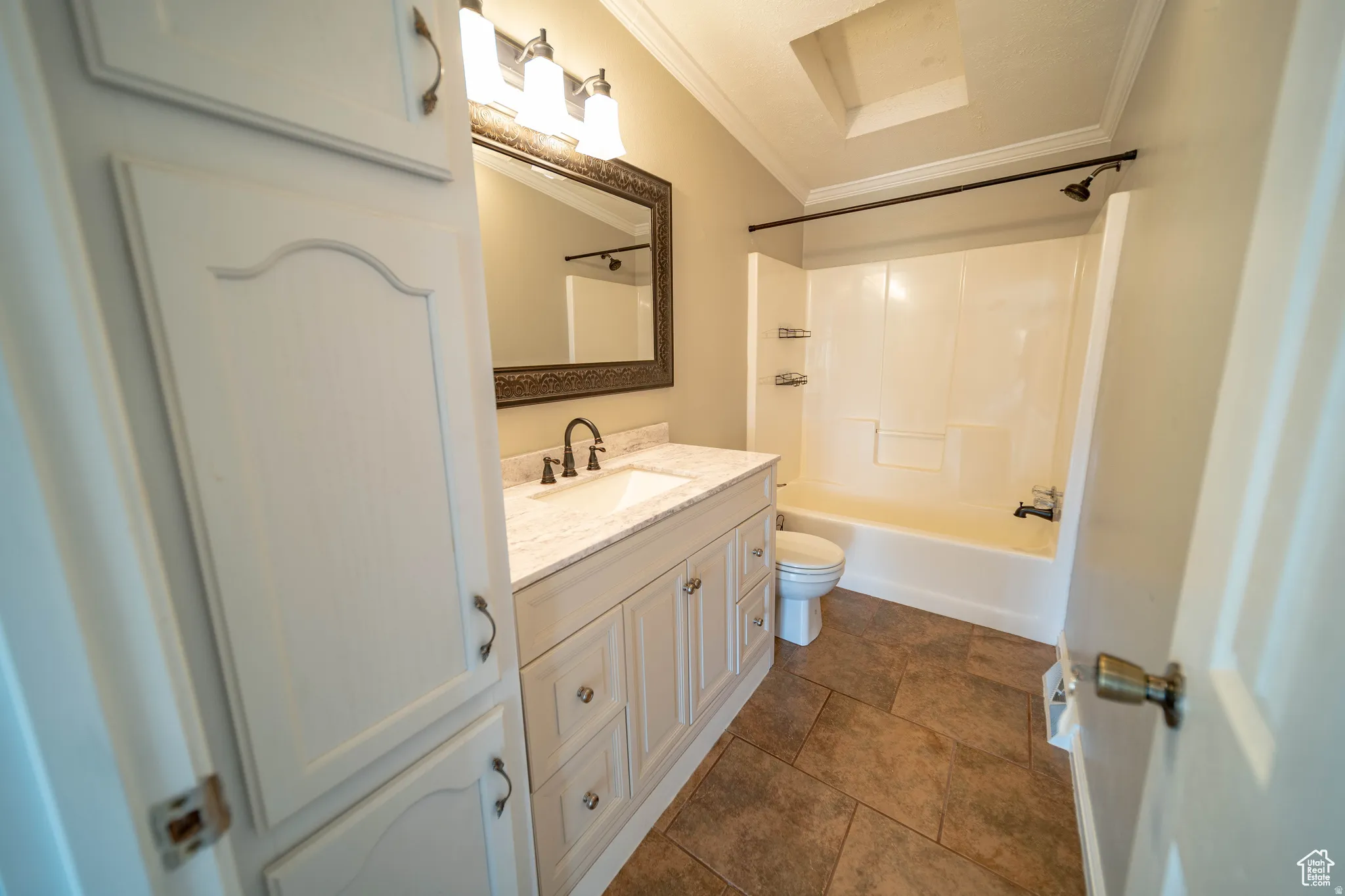 Full bath with vanity, crown molding, shower / bathtub combination, and dark tile patterned flooring