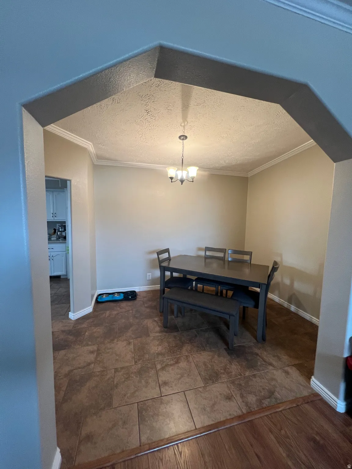 Dining area with a textured ceiling, ornamental molding, and a chandelier