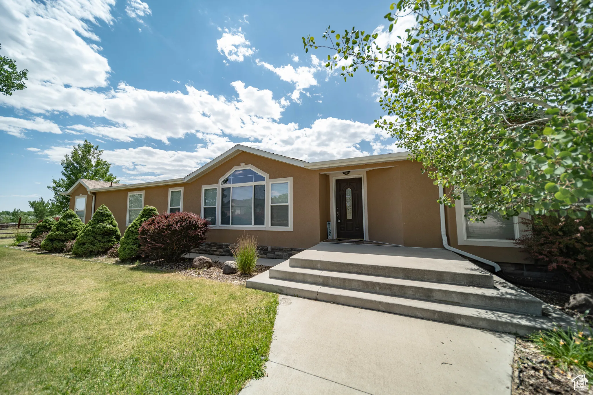 Ranch-style house with stucco siding and a front yard