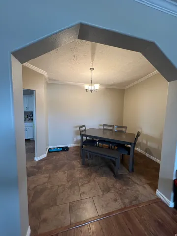 Dining area with a textured ceiling, ornamental molding, and a chandelier