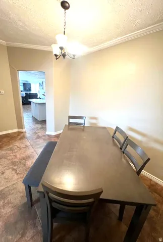 Dining area featuring a textured ceiling, ornamental molding, and hanging lights