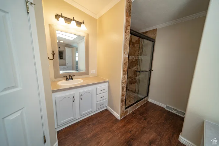 Full Mater Bathroom with vanity, a stall shower, ornamental molding, and dark wood-style floors
