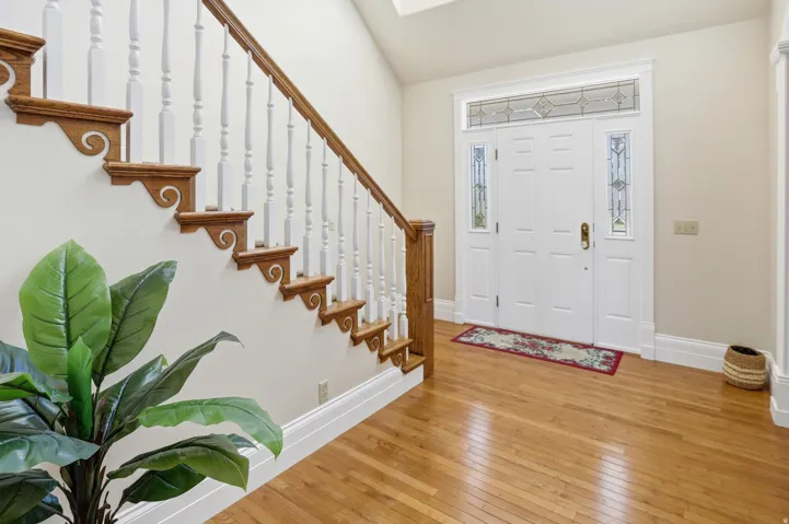 Entrance foyer with hardwood / wood-style floors and vaulted ceiling