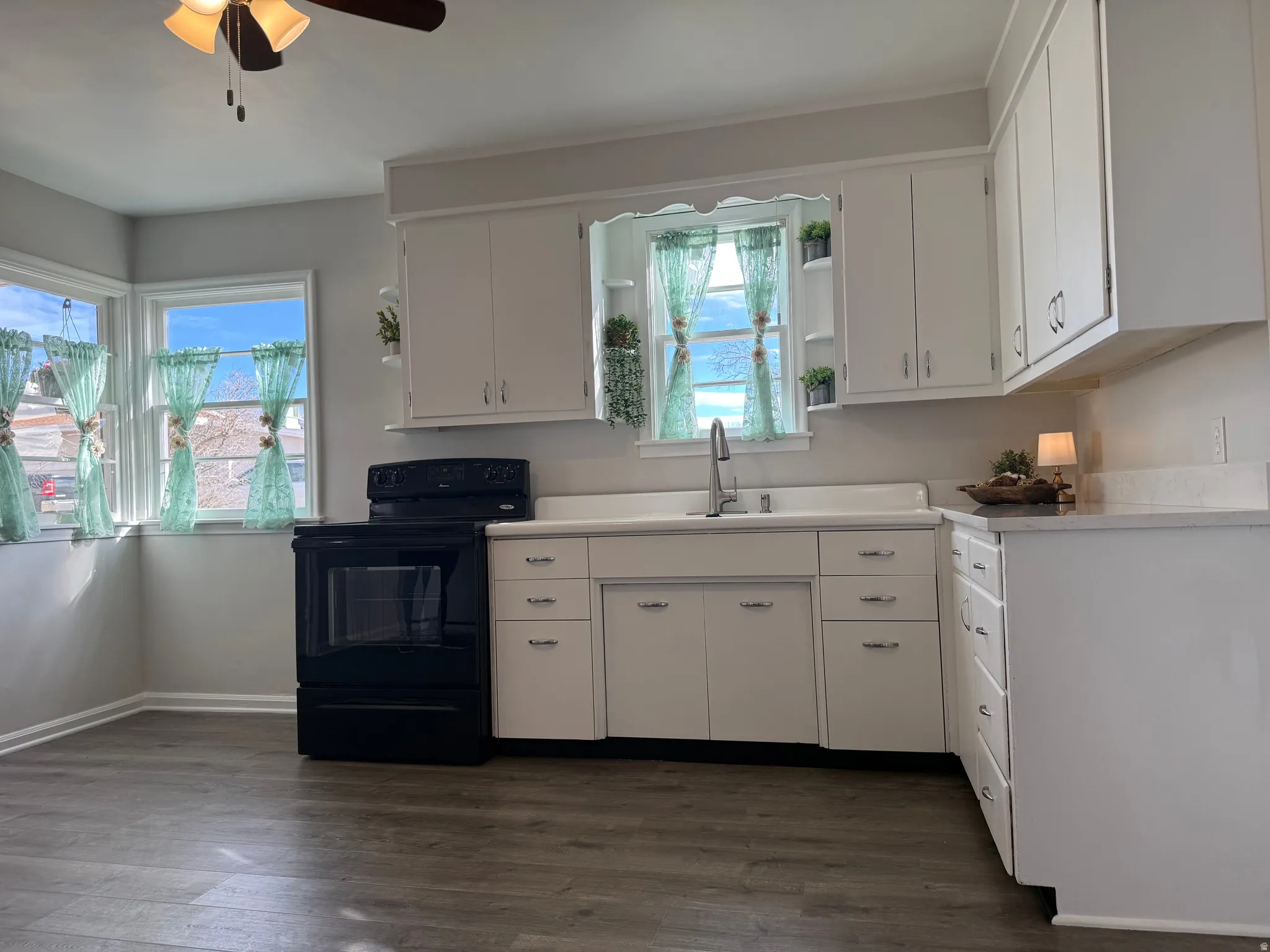 Kitchen featuring light countertops, black electric range oven, white cabinetry, and open shelves