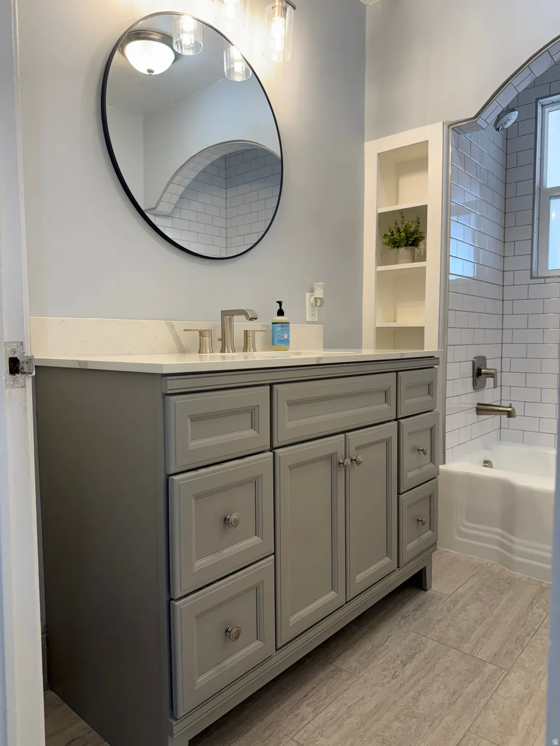 Full bathroom featuring built in shelves, vanity, and shower / tub combination