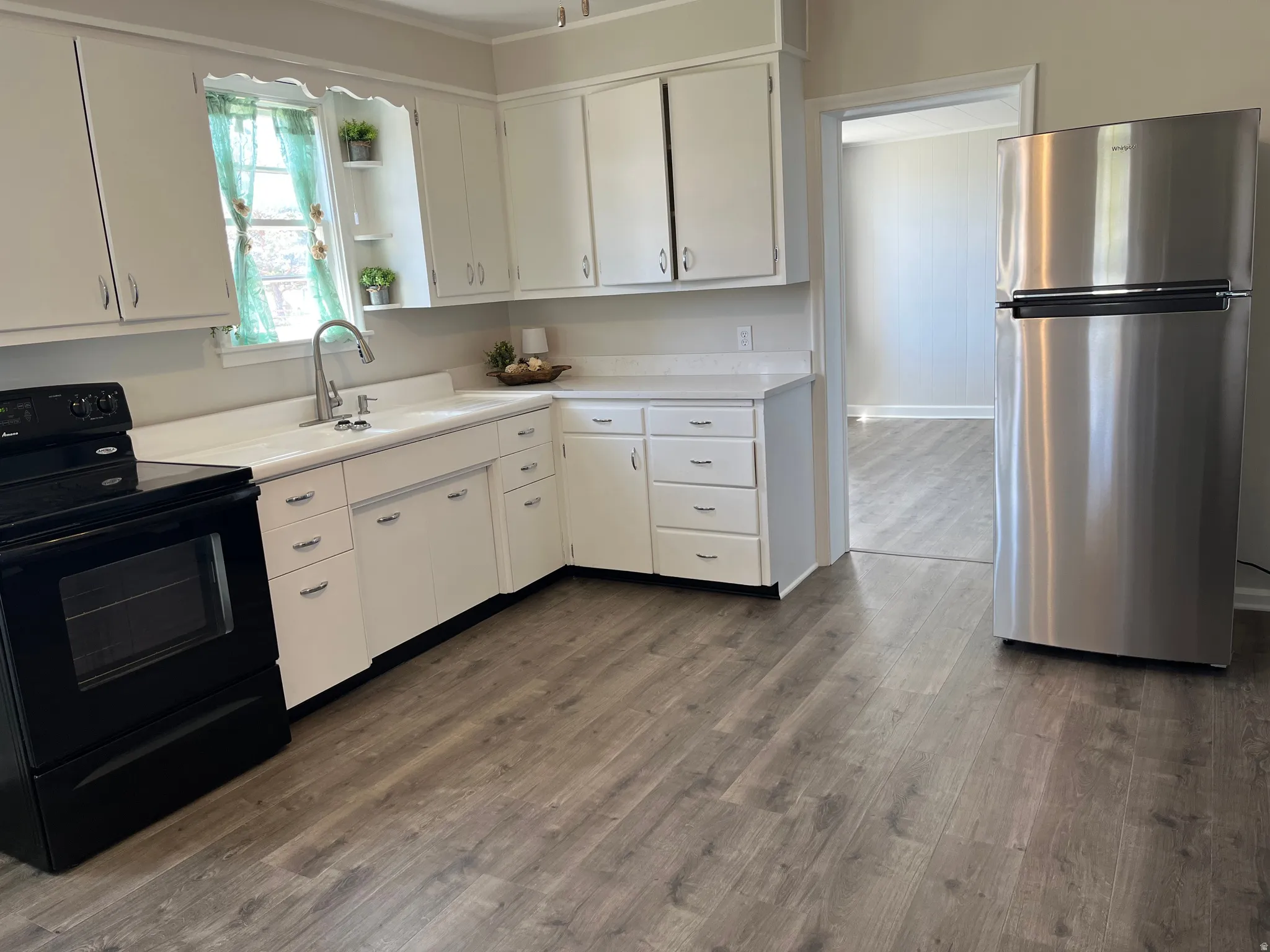 Kitchen featuring wood-finish flooring, white cabinetry with chrome hardware, a white countertop, and a stainless steel refrigerator