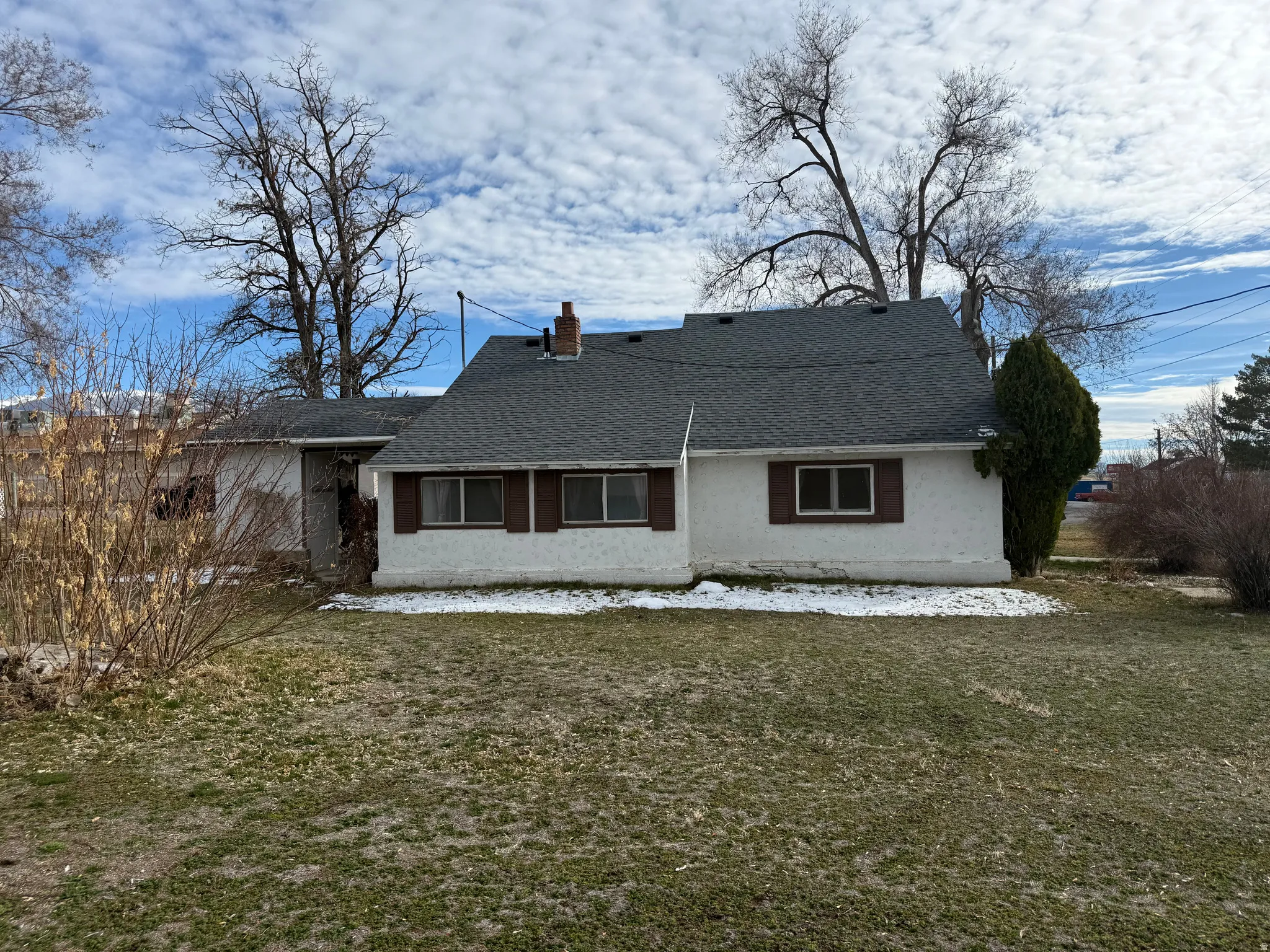 Back of property with roof with shingles, a chimney, a yard, and stucco siding
