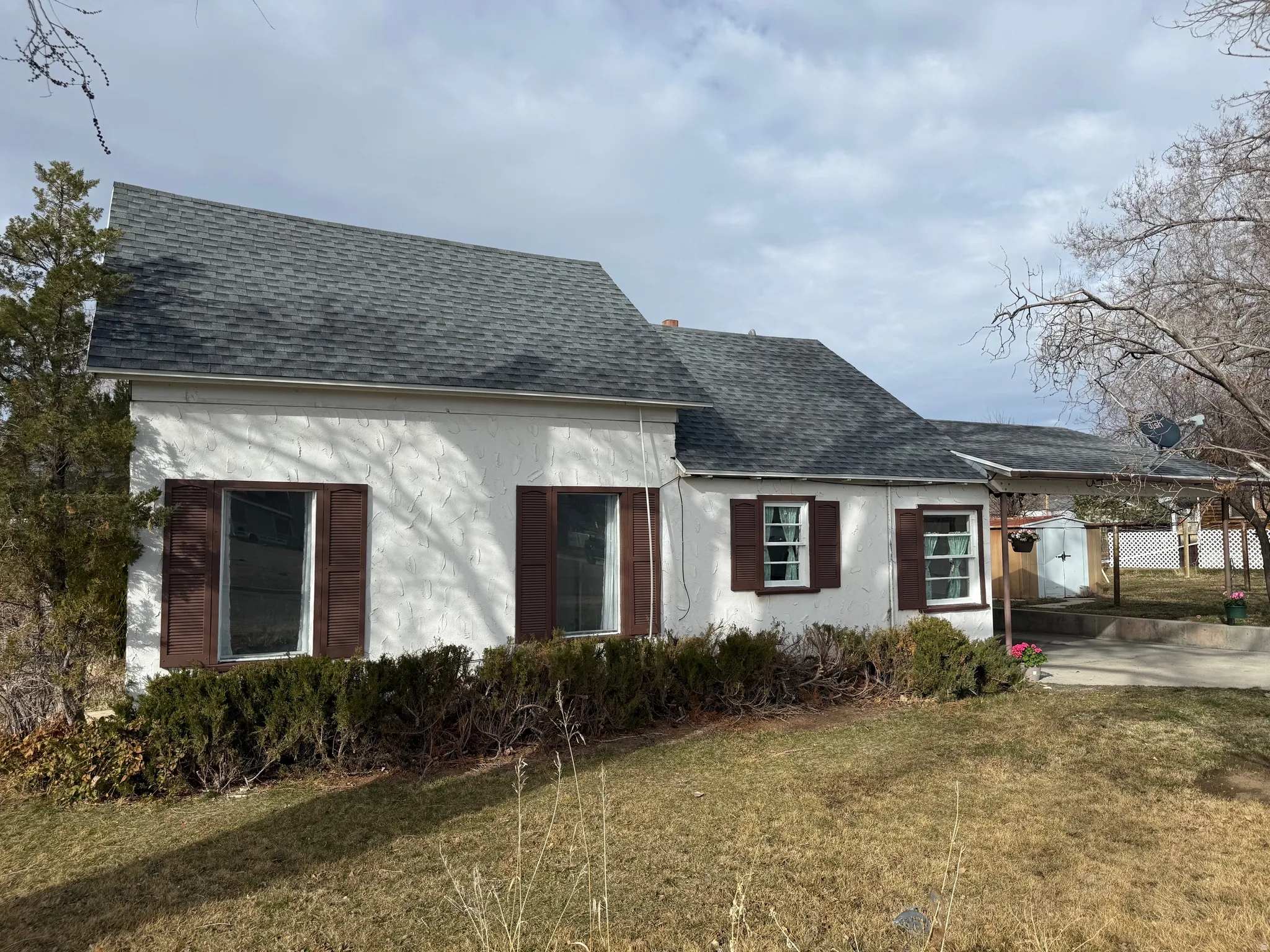 View of front of property with roof with shingles, stucco siding, and an attached carport
