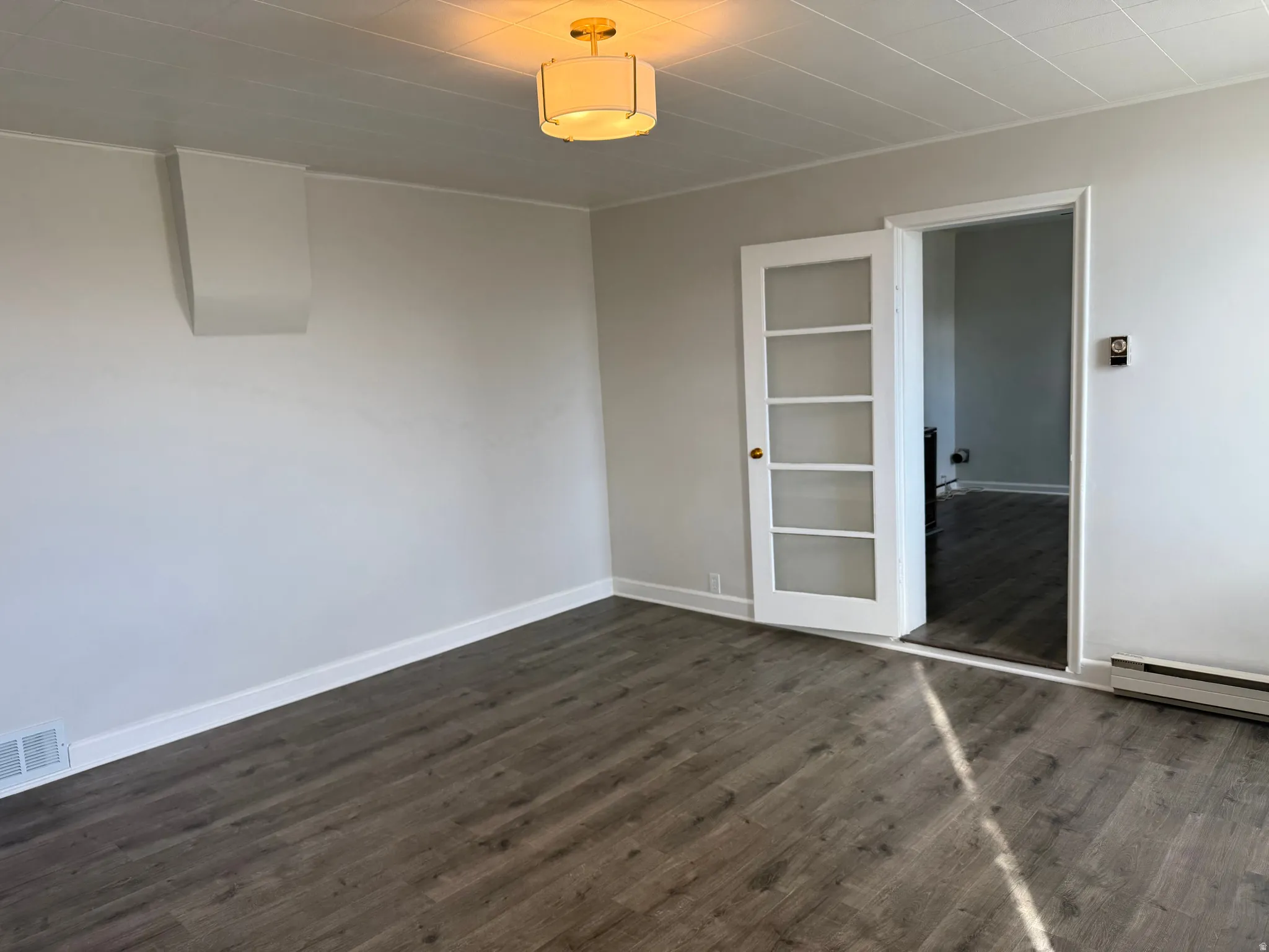 Unfurnished bedroom featuring dark wood-type flooring and baseboards