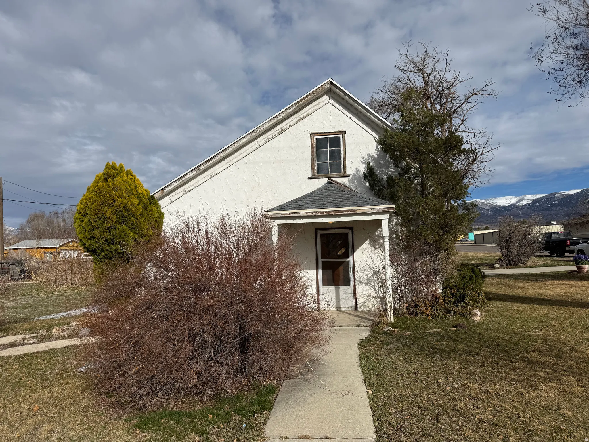 View of front of house featuring a front yard, a shingled roof, stucco siding, and a mountain view