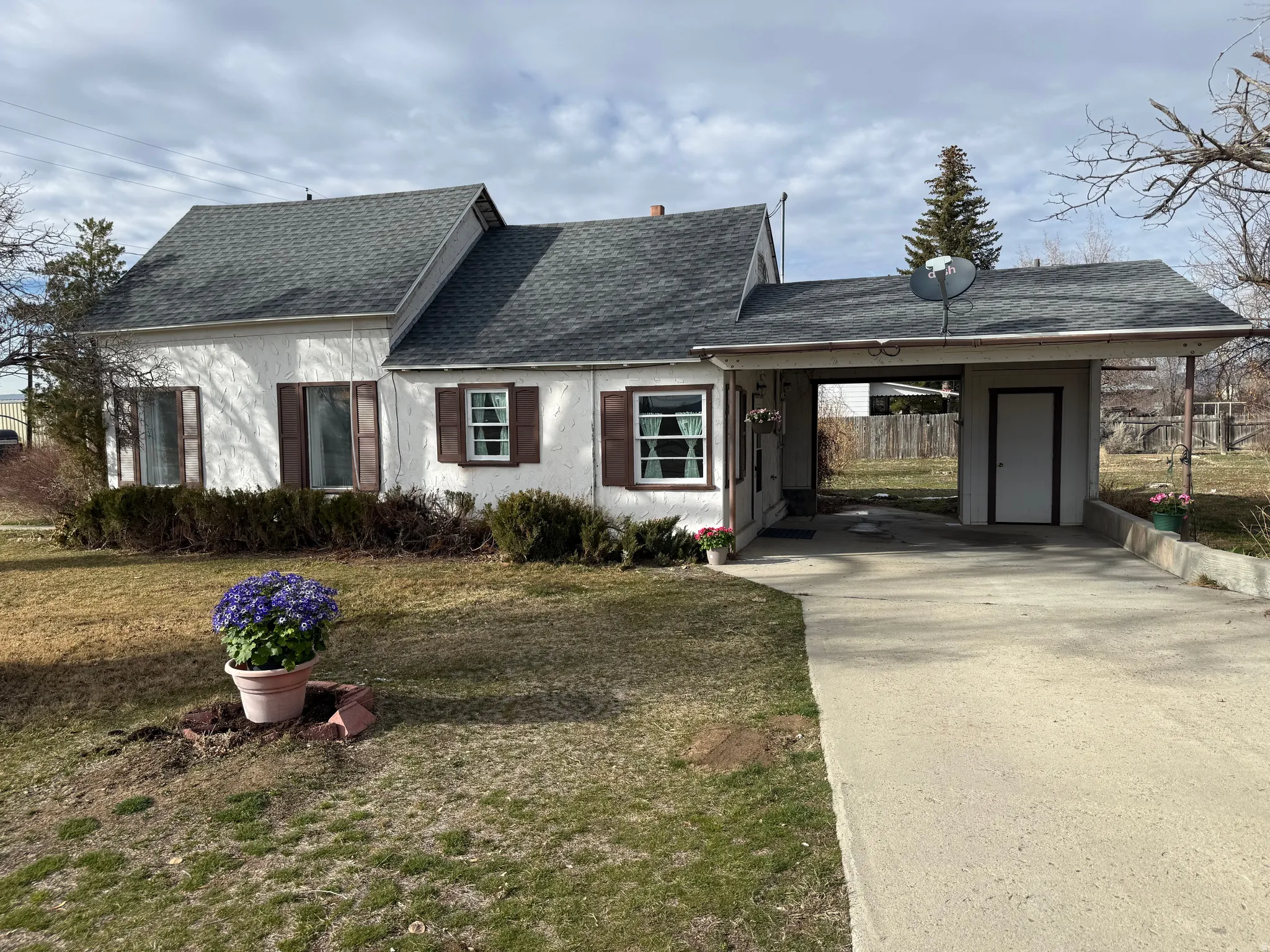 View of front of home with roof with shingles, a carport, driveway, a front yard, and stucco siding