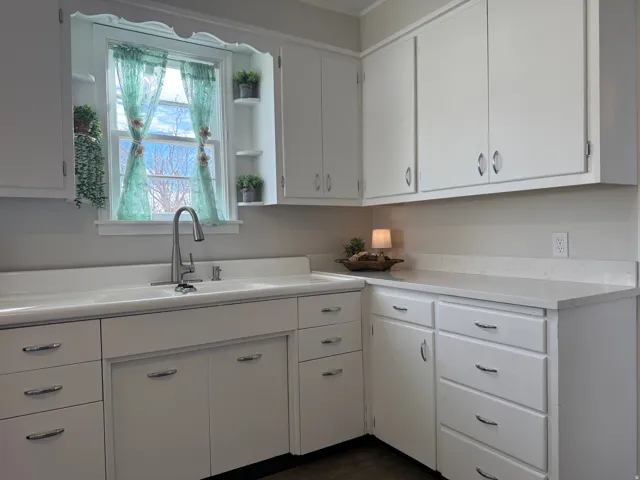 Kitchen featuring white cabinetry, light countertops, open shelves, and dark wood-style flooring