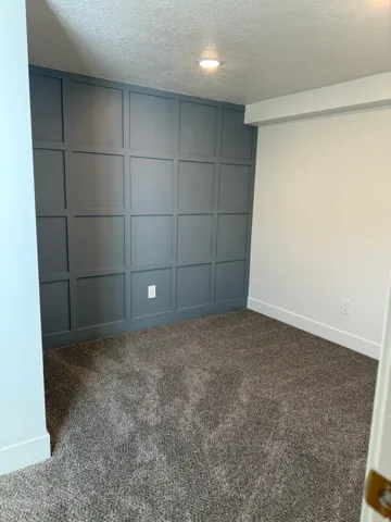 Spare room featuring a decorative wall, dark carpet, and a textured ceiling