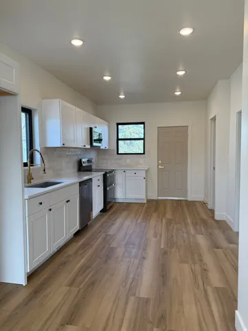 Kitchen featuring white cabinets, stainless steel appliances, decorative backsplash, light wood finished floors, and recessed lighting