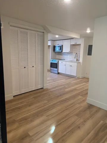 Kitchen with white cabinetry, stainless steel appliances, light wood finished floors, light countertops, and electric panel