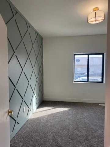 Unfurnished room featuring an accent wall, carpet floors, and a decorative wall