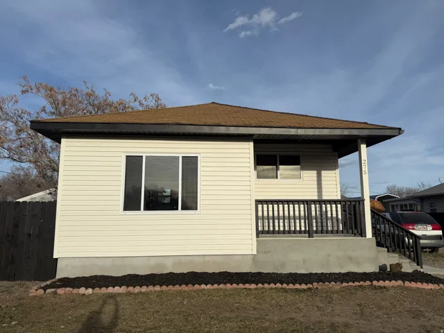 View of side of home featuring a shingled roof and covered porch