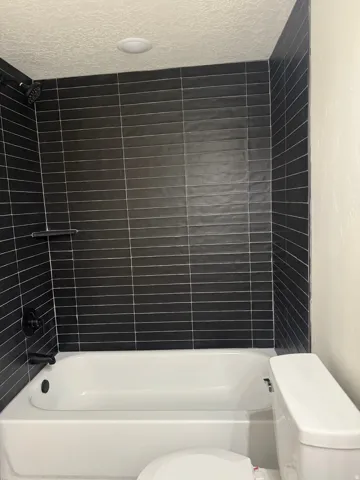 Bathroom featuring a textured ceiling and shower / bathtub combination