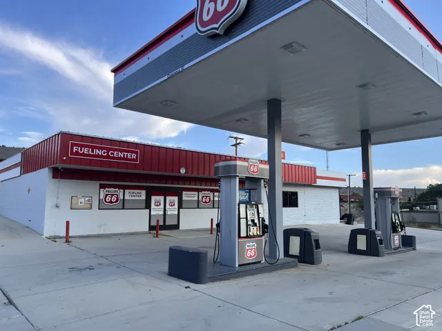 Commercial fueling center featuring a high-clearance metal canopy, concrete apron, and multiple fuel pump islands