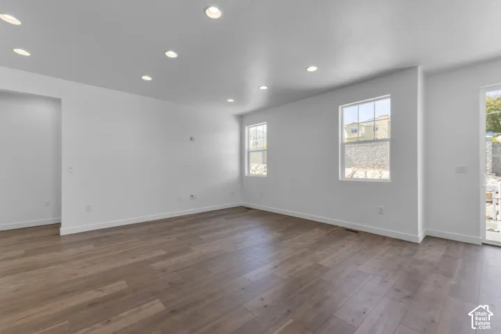 Recessed lighting, wood-finish flooring, two large windows, and a sliding glass door