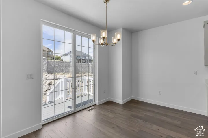 Sliding glass door with grid panes, wood-finish flooring, gold-finish chandelier with seeded glass shades, and white baseboards