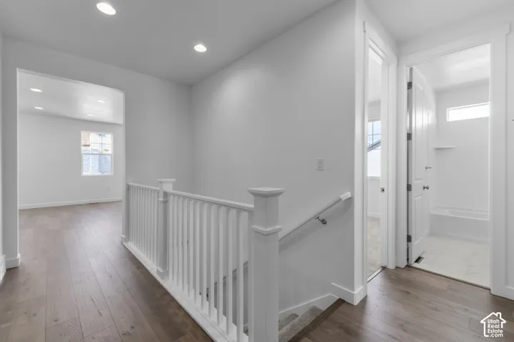 Wood-finish flooring throughout, white baluster railing, recessed lighting, and white interior doors