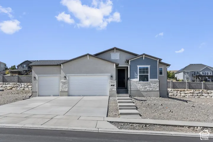 Two-car garage, concrete driveway, stone and siding exterior accents, concrete walkway, and a dark entry door