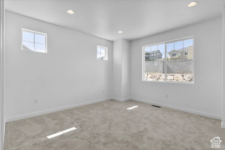 Recessed lighting, multiple windows, plush carpet flooring, and white painted walls