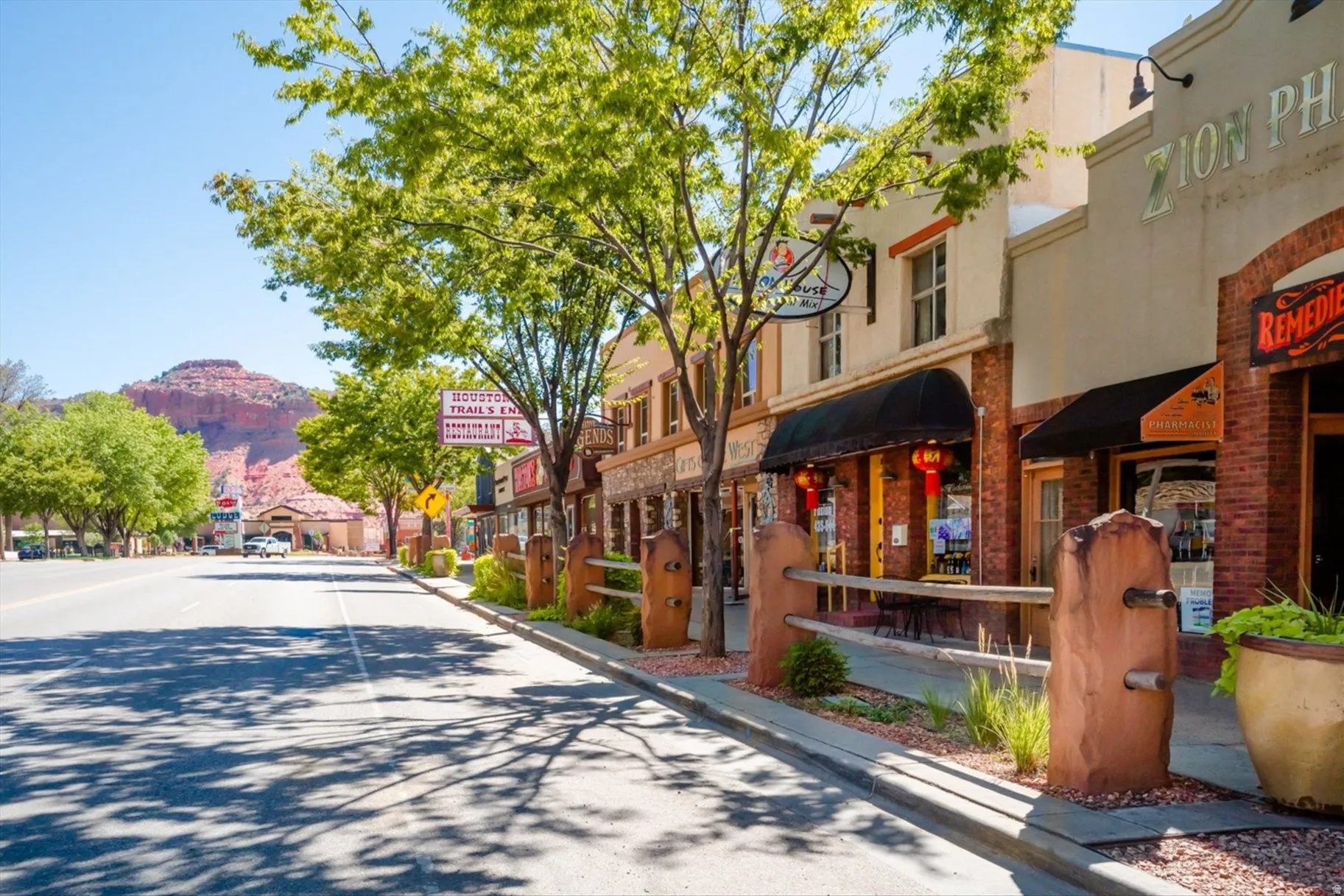 Commercial storefronts with brick and stucco facades, dark awnings, and a concrete sidewalk