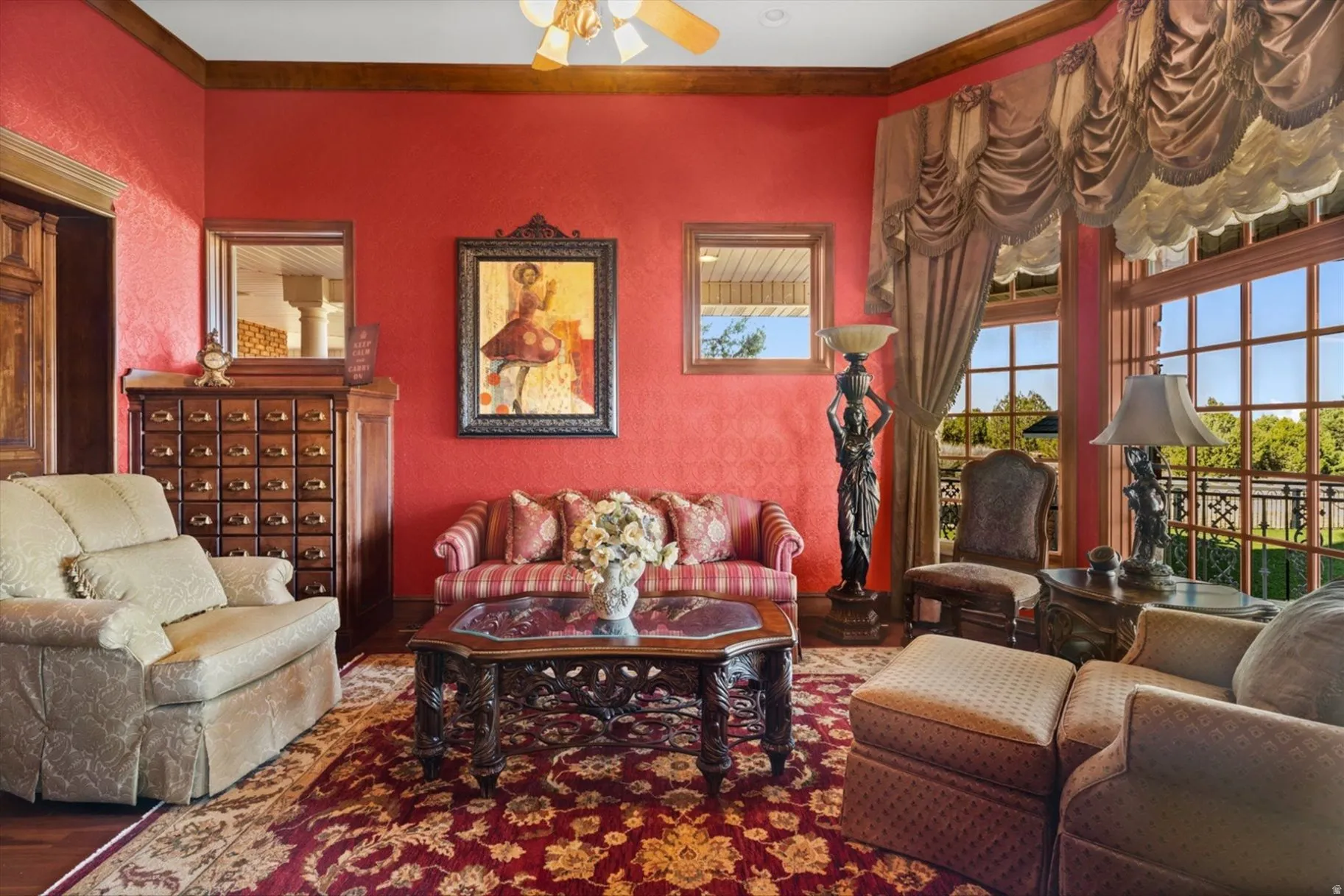 Expansive windows with custom drapery, detailed wood trim, and a ceiling fan