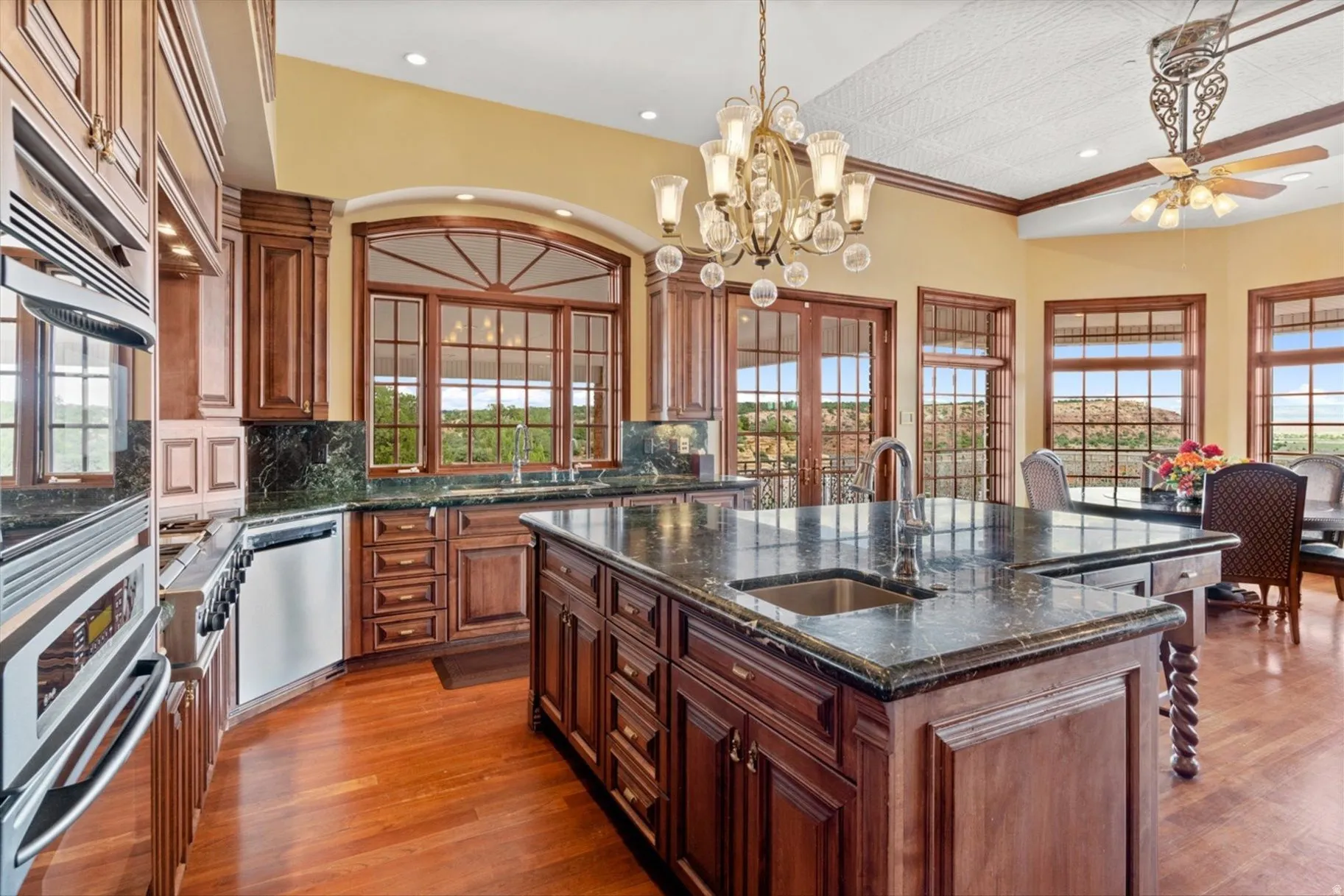 Custom cabinetry, built-in stainless steel appliances, central island with integrated sink, stone countertops, and wood-finish flooring