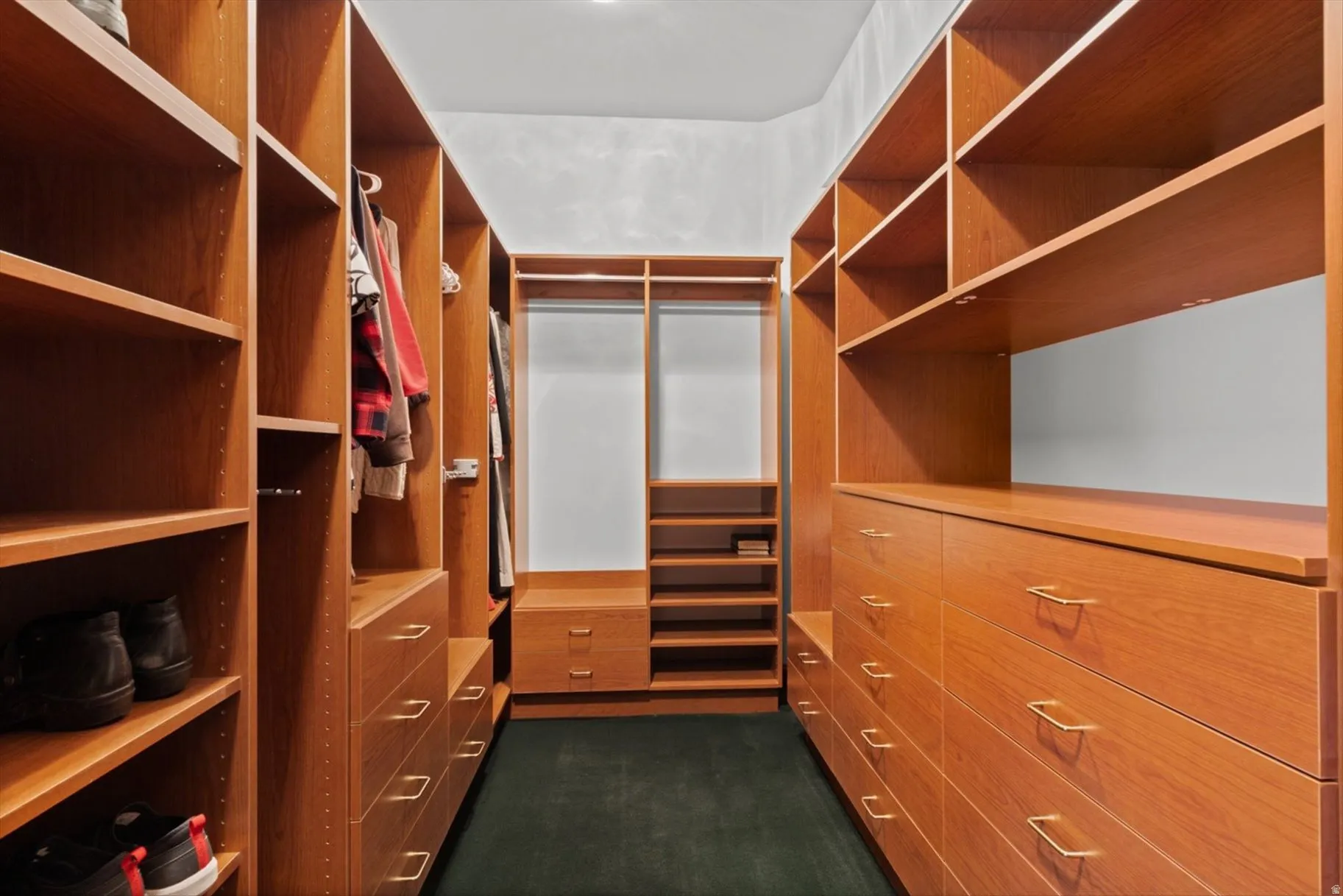 Expansive custom built-in closet system featuring warm wood-finish cabinetry, integrated shelving, multiple hanging rods, and ample drawer storage with polished hardware