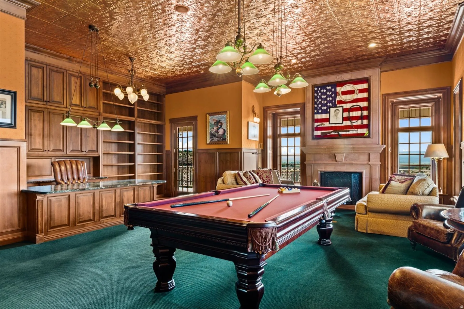Recessed fireplace with stone surround, wood-paneled walls, built-in wooden cabinetry, custom built-in shelving, and a decorative ceiling