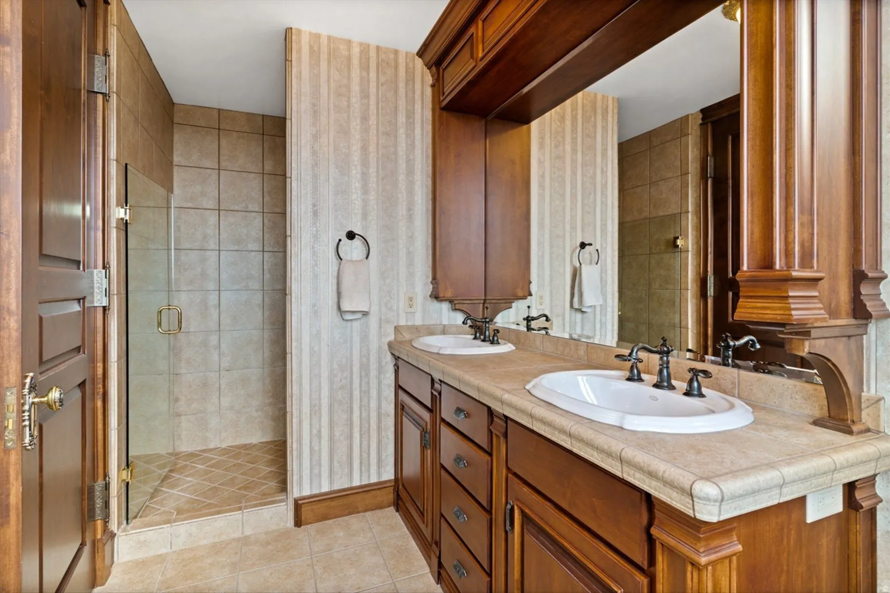 Dual vanity with wood cabinetry, integrated sinks, and dark bronze fixtures