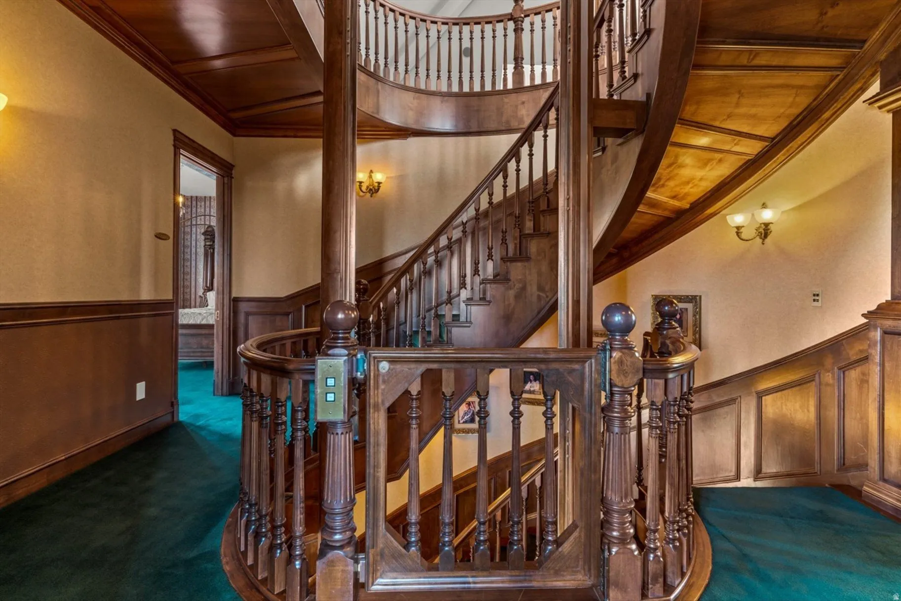 Curved wood staircase with intricate baluster detailing, wood paneling, and wood-finish ceiling accents
