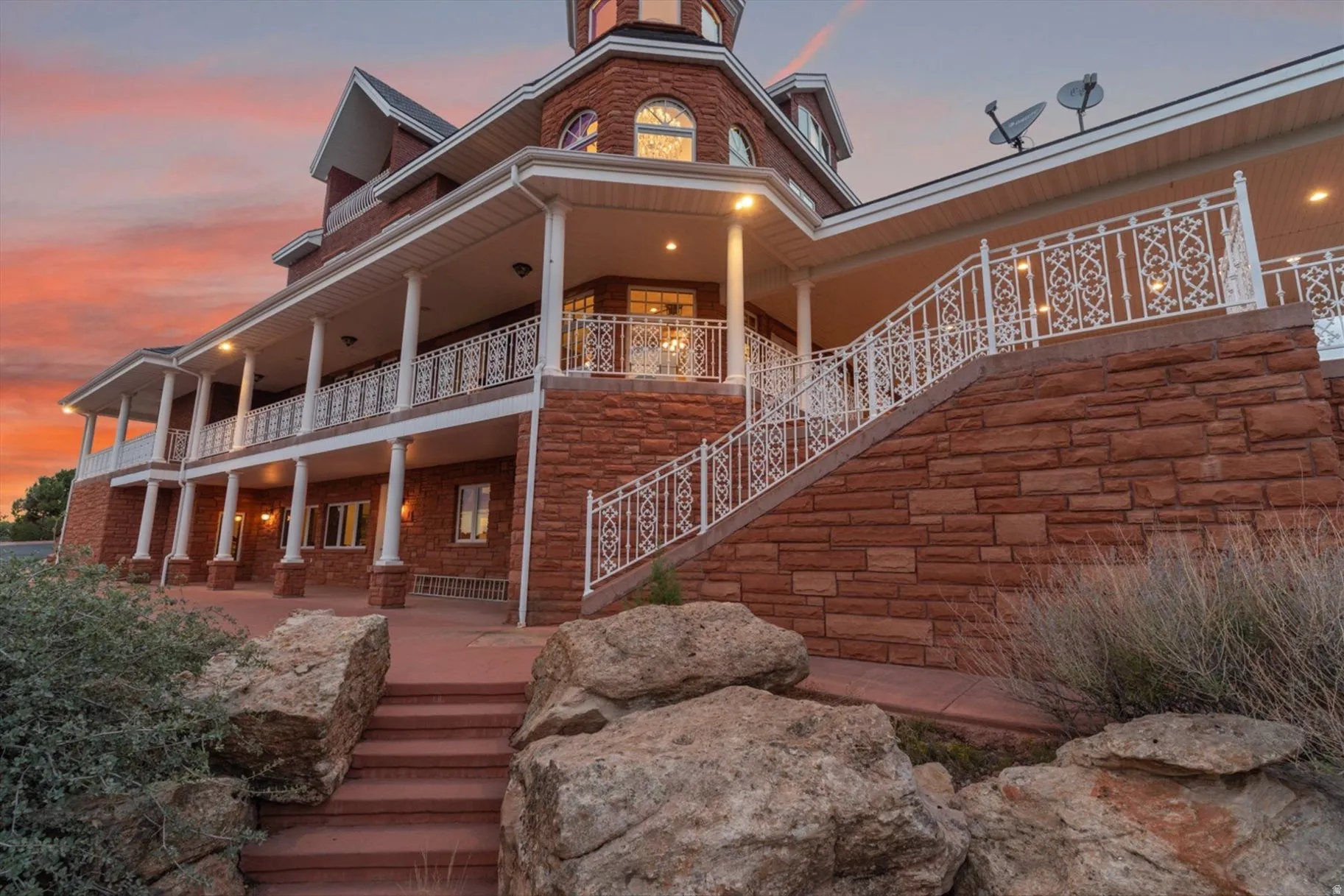 Multi-level facade featuring red stacked stone and a wrap-around covered porch