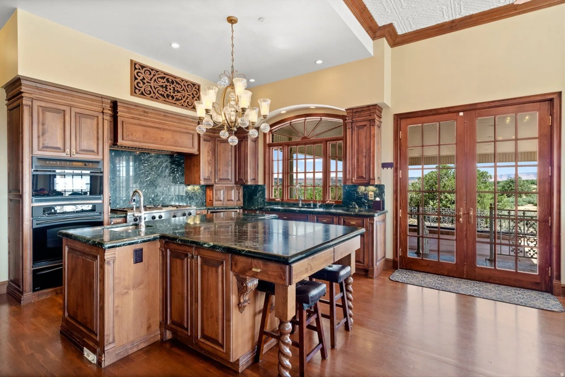 Hardwood flooring throughout, custom wood cabinetry, stone countertops, integrated double ovens, and glass-paneled double doors