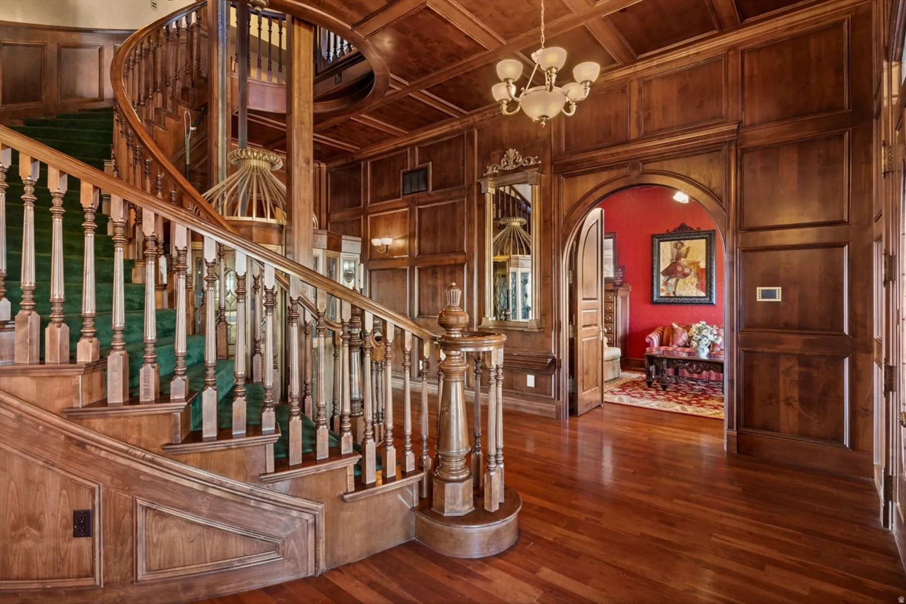 Grand wooden spiral staircase with a green runner