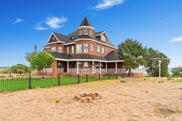 Brick exterior with a turret, multiple dormer windows, and a wraparound porch